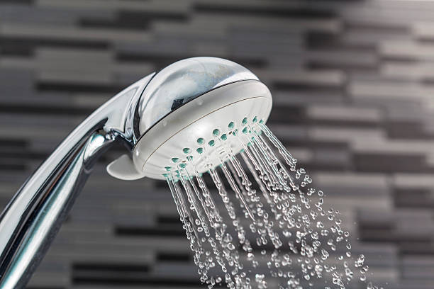 Shower head with water drops falling on a bathroom Silver shower head on a bathroom with water drops falling on a bathroom textured background shower head stock pictures, royalty-free photos & images