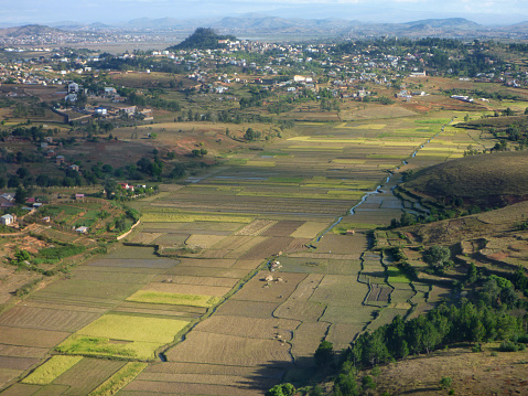Just outside the highlands of Antananarivo, homes and agricultural fields stand on top of the heavily terraced hillsides with lush green rice paddy fields below standing in the muddy river valley.