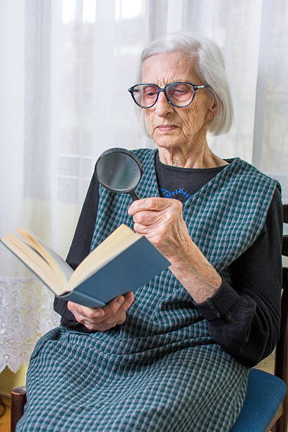 istock Grandma reading a book through magnifying glass 514067138