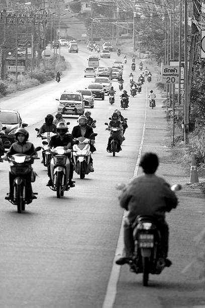 Kigali, Rwanda – December 15, 2025: A red electric motorcycle taxi featuring a prominent yellow battery casing. The panning shot documents the use of zero-emission vehicles in the city's public transport sector during the rainy season.