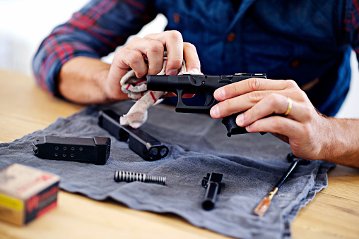 Cropped view of a man cleaning his gun