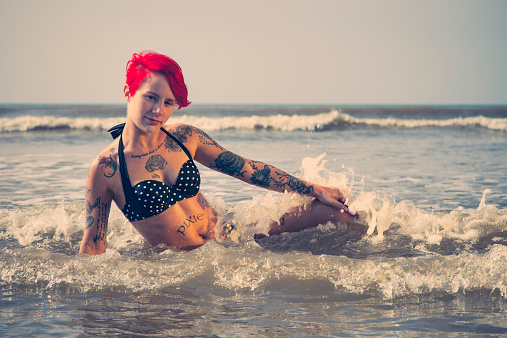 Retro-style photo of a redhead wearing a polka dot bikini bathing in the sea.