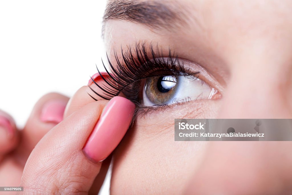 Woman applying false eyelashes Close-up of a woman applying false eyelashes Adult Stock Photo