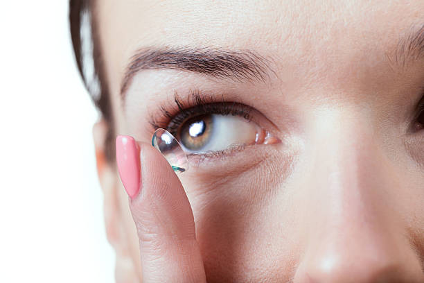 Inserting a contact lens in female eye