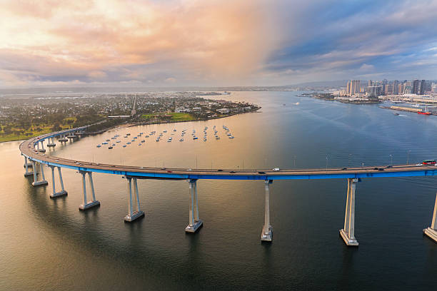 The Coronado Bridge At Dusk From Above The iconic Coronado Bridge spanning the San Diego Bay with the city's skyline in the background shot at dusk after a storm began to clear.  I shot this photograph from approximately 300 feet in elevation during a chartered helicopter photo-flight of the region. san diego photos stock pictures, royalty-free photos & images