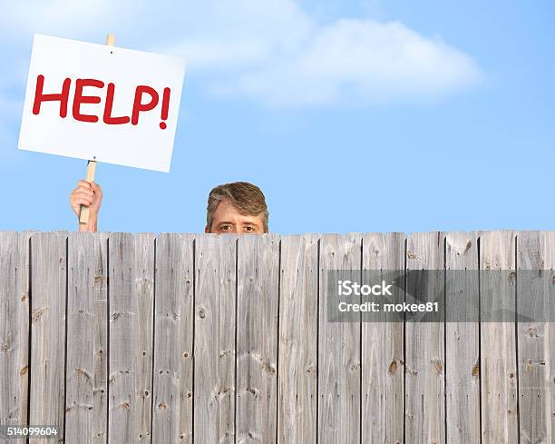 Man With Help Sign Looking Over Wood Privacy Fence Stock Photo - Download Image Now - Neighbor, Mischief, Abuse