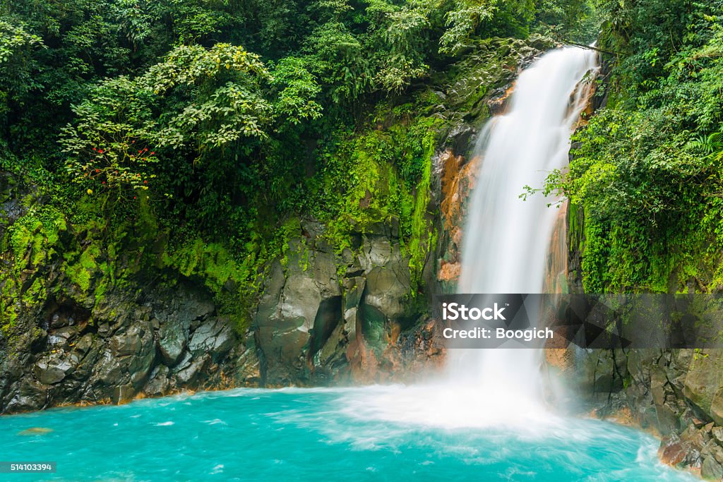 Costa Rica Nature Background Travel Destinations Rio Celeste This is a horizontal, royalty free stock photograph of scenic Costa Rica, a Central American travel destination. The Rio Celeste waterfall is a natural landmark for eco tourists visiting Tenorio National Park. The flowing water falls over a rocky cliff, through green rainforest vegetation, and pools into an aqua color at the base. Photographed with a Nikon D800 DSLR camera. Waterfall Stock Photo