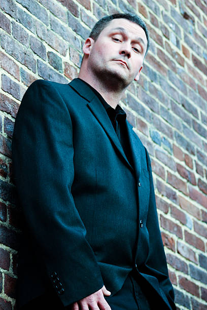 istock Close-up of Well-dressed Man Leaning Against Brick Wall 514104734