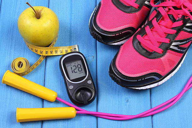 Glucometer, sport shoes, fresh apple and accessories for fitness stock photo