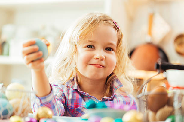 Cute little girl holding easter egg. The natural dyed eggs are decorated in a basket.