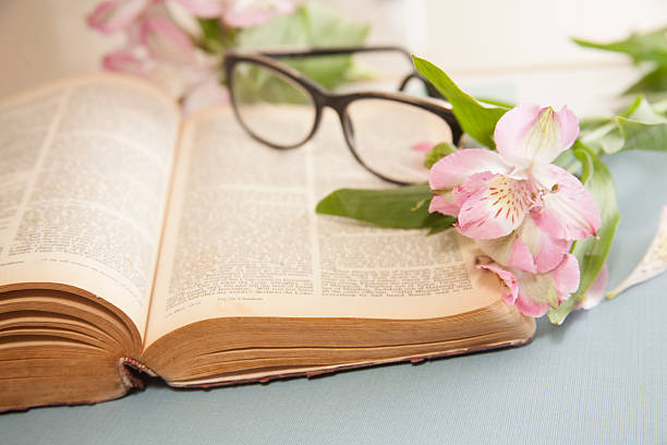 Open antique book with vintage glasses. Old round spectacle.