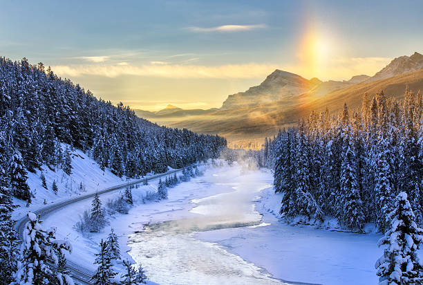 Foggy Valley This picture was taken in the winter of Canadian Rockies. It was a cold winter morning. This spot was sort of far away from our hotel. It is absolutely worth. The vibrant colors of a warm sunrise reflected in the cool waters of the bow river. snow river stock pictures, royalty-free photos & images