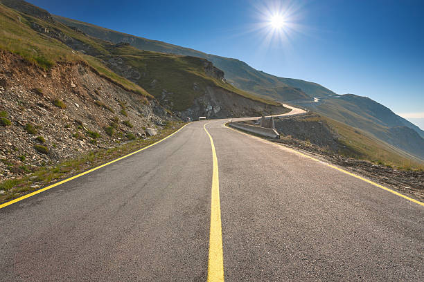 istock Driving on an empty mountain road towards the sun 514112062