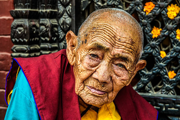 Kathmandu, Nepal - October 28, 2015 : Very old tibetan buddhist nun sitting outside a shrine in Kathmandu