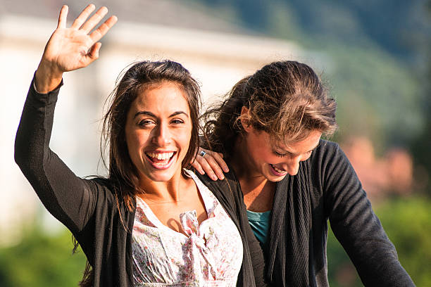 Cheerful friends, two Hispanic women. enjoying a sunny day outdoors in the city.