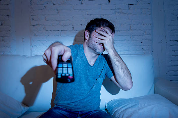 istock man watching horror movie television blocking his eyes scared 514115668