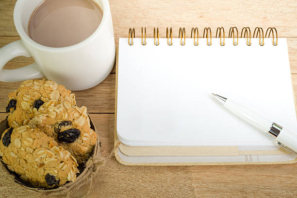 Blank notebook with coffee and oat cookies on wood background