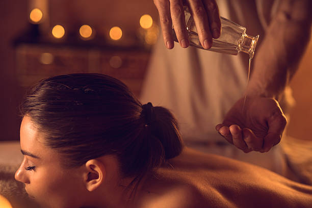 gros plan d'un masseur qui consiste à verser de l'huile de massage à la main. - huile de massage photos et images de collection