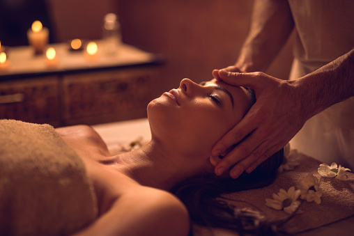 Relaxed woman receiving facial massage at the spa and relaxing with her eyes closed.