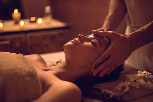 Young woman enjoying during head massage at the spa. Relaxed woman receiving facial massage at the spa and relaxing with her eyes closed. facial massage stock pictures, royalty-free photos & images