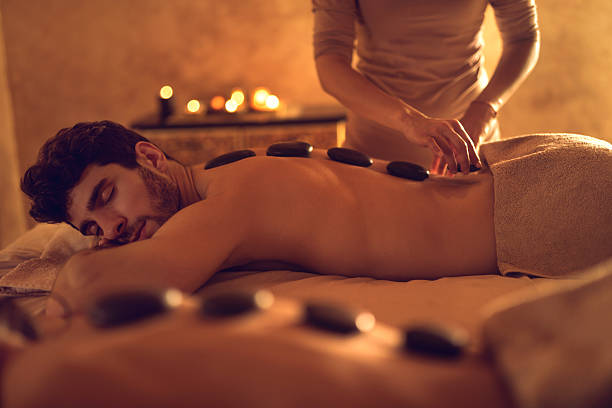 hombre joven disfrutando durante la terapia de piedras calientes en el spa. - lastone therapy pampering spa treatment women fotografías e imágenes de stock