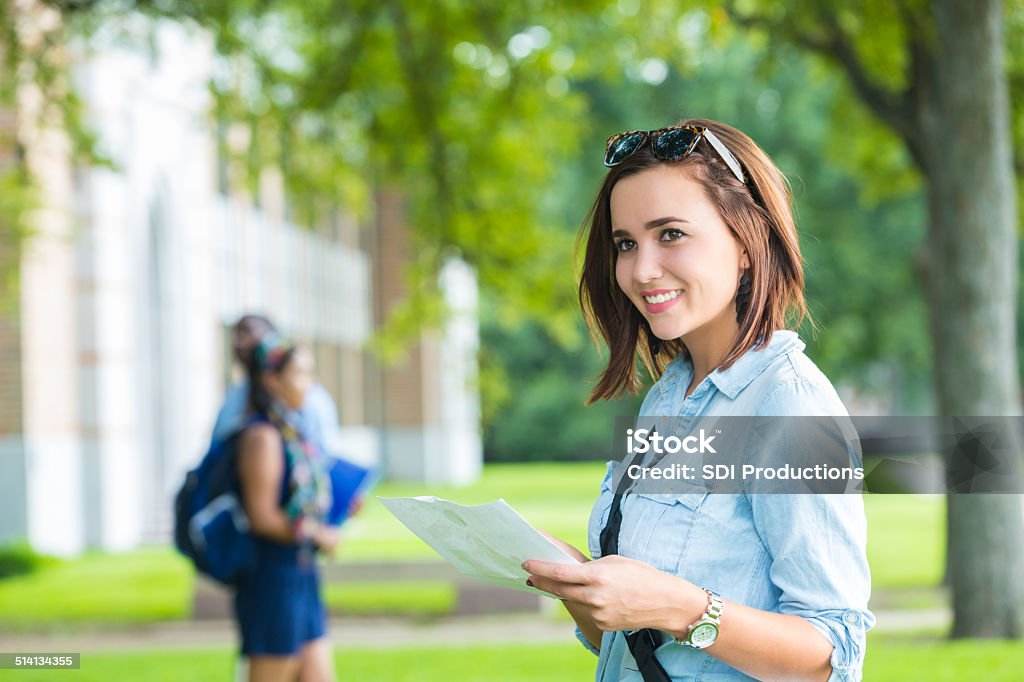 Happy college student using campus man while walking to class Young college student studying class schedule or campus map  University Stock Photo