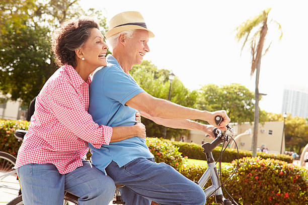 senior hispano montar bicicletas de pareja en el parque - senior adult healthy lifestyle exercising cycling fotografías e imágenes de stock