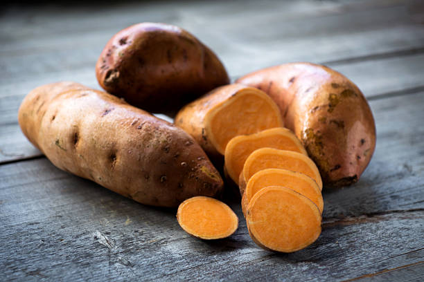 Raw sweet potatoes on wooden background closeup Raw sweet potatoes on wooden background closeup sweet potato photos stock pictures, royalty-free photos & images