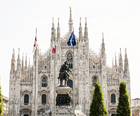 Milan cathedral (Duomo di Milano) with statue of Vittorio Emanuele II and flags of Italy and the European Union. Cultural heritage.