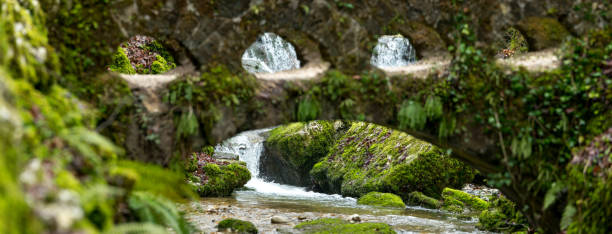 Moss covered bridge and river in Verenaschlucht, Solothurn, Switzerland. Focus on waterfall in background with blurry bridge in foreground.