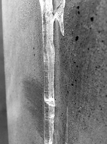 This image was taken on a winters day in Berlin. It shows an icicle that clings on a stone and sunlight is reflecting on it.