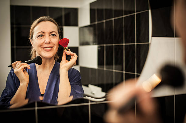 Mature Woman with makeup brushes in the Mirror