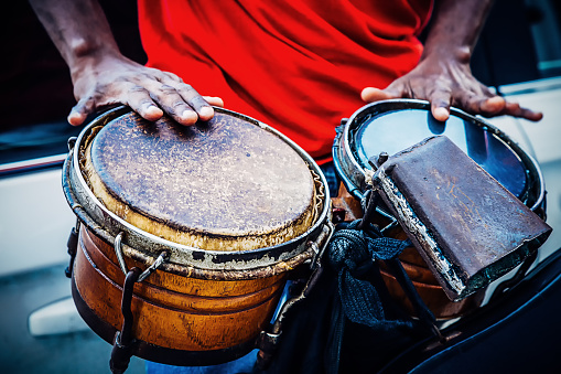 Hands of Cuban street band drummer hitting drums.