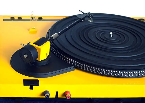 Turntable with black tonearm in yellow case with rubber mat on disc with stroboscope marks with output connectors rear view isolated on white background. Horizontal view closeup