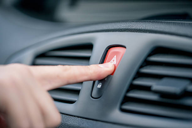 Man Pushing Hazard Lights Button on Car Dashboard stock photo