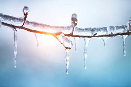 Dangerous icicles hang from roof of the house. Big icicles in the streets of the winter town. Winter time