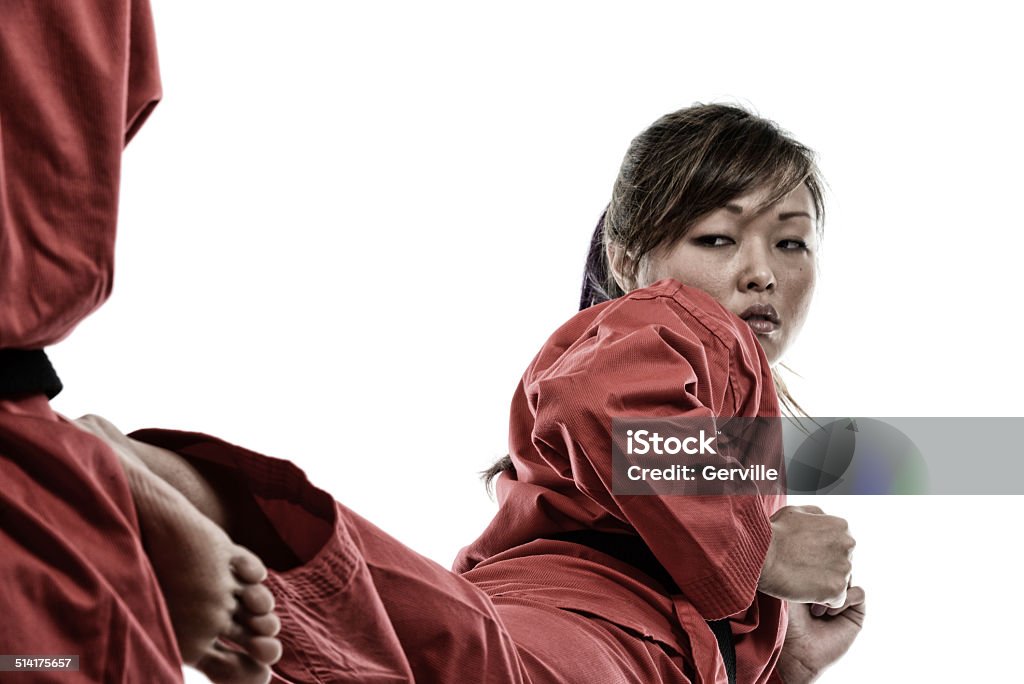 Korean Karate Side Kick Martial artist executing a side kick on her opponent (The woman kicking has purple highlights in her hair). Adult Stock Photo