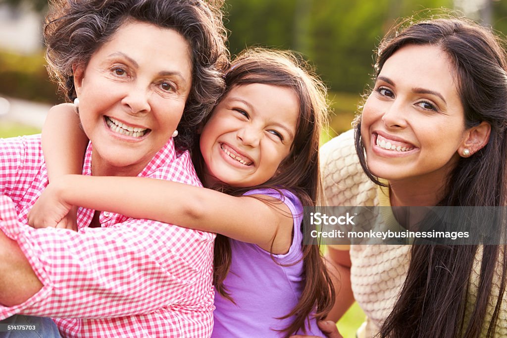 Grandmother With Granddaughter And Mother In Park Grandmother With Granddaughter And Mother In Park Smiling To Camera Latin American and Hispanic Ethnicity Stock Photo