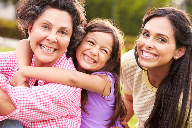 Grandmother With Granddaughter And Mother In Park Grandmother With Granddaughter And Mother In Park Smiling To Camera hispanic grandmother stock pictures, royalty-free photos & images