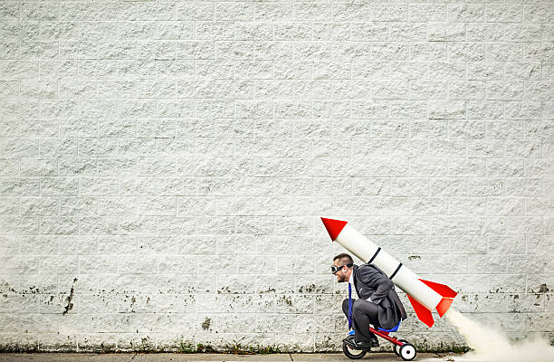 Moving forward Businessman riding a tricycle and getting help from the rocket strapped to his back :-) taking off activity stock pictures, royalty-free photos & images