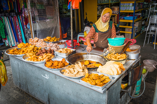 Kuala Lumpur, Malaysia - 26th June 2014: Woman in headscarf cooking delicious fried snacks at a street food stall in a market in Chow Kit in the heart of downtown Kuala Lumpur, Malaysia's vibrant capital city.