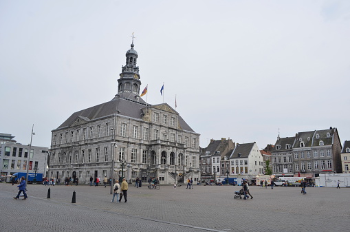 Maastricht, Netherlands, April 12, 2014: View over town hall on markt in Maastricht where people are passing by during one cloudy day in mid-spring.