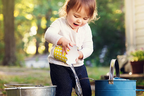 istock Happy toddler girl playing with watering cans 514222876