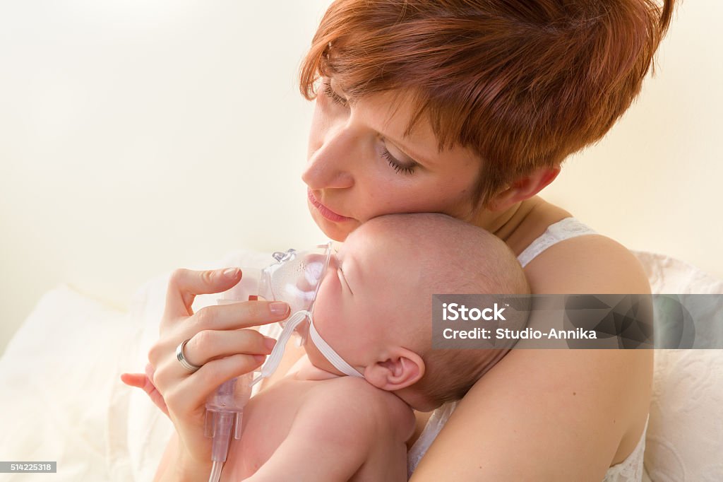 Loving mom treating sick baby Sick baby of 7 weeks old getting treatment with nebuliser or aerosol Asthmatic Stock Photo