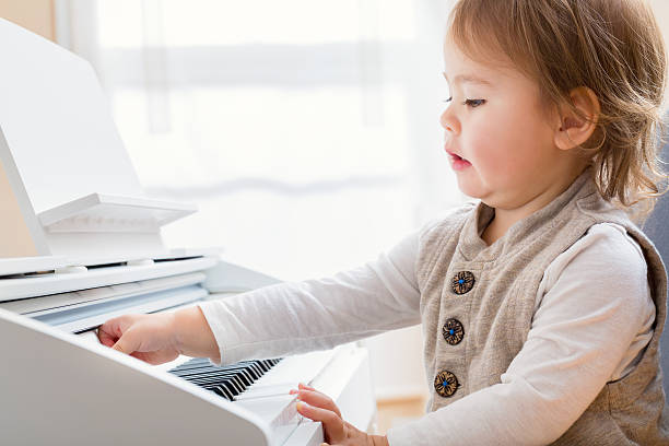 istock Toddler girl making a funny expression while playing piano 514225954