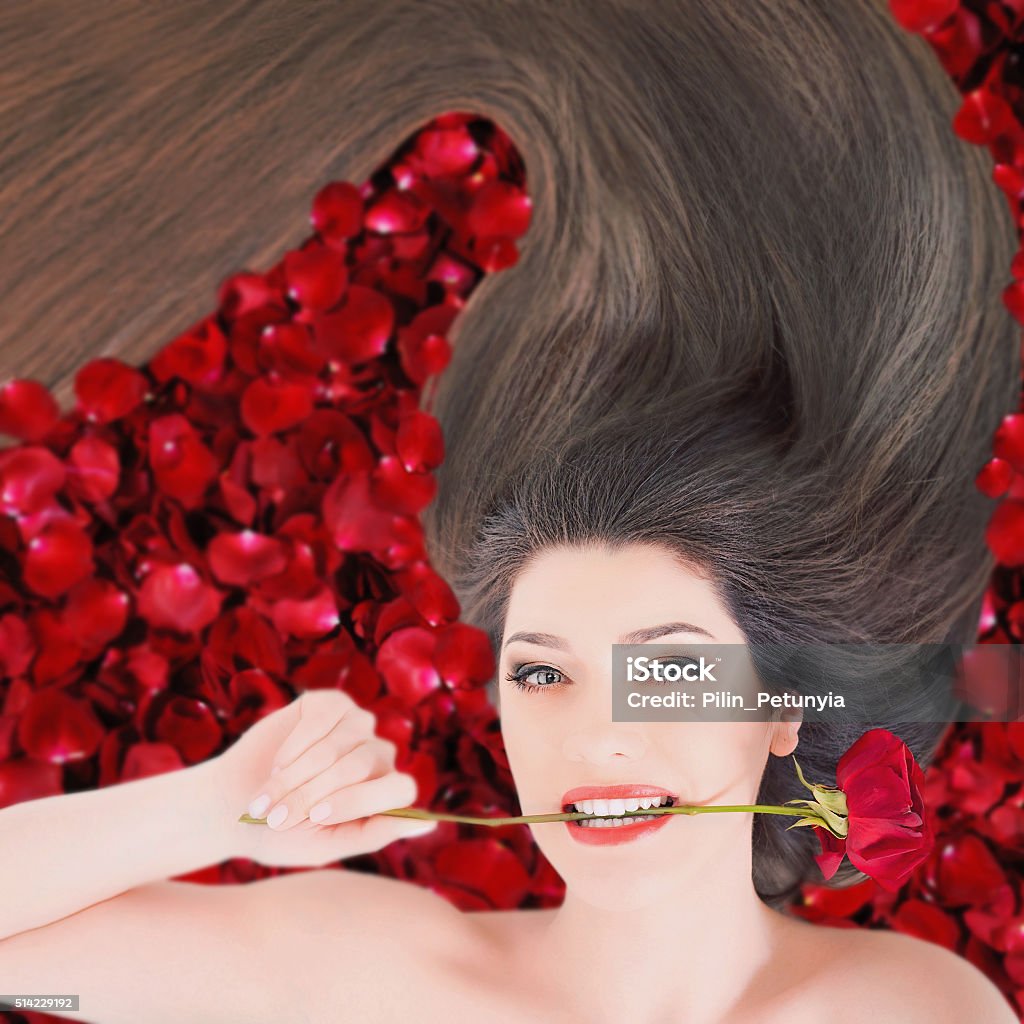 Happy woman with beautiful makeup and hairstyle Happy woman with long beautiful hair at red rose petal background. Perfect hairstyle. Beauty and fashion. Hair care. Girl holding a flower of red rose. International Women's Day. Eighth march Abstract Stock Photo