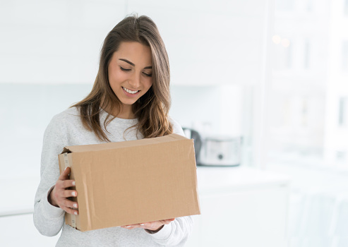 Young woman at home holding a package and smiling - delivery concepts