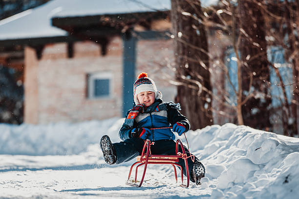 маленький мальчик на сани - little boys sled clothing slide стоковые фото и изображения