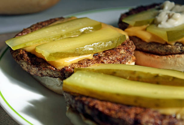 Cheeseburgers With Pickle Barbecued Cheeseburgers just of the grill with sliced dill pickles on a toasted bun dill pickle stock pictures, royalty-free photos & images