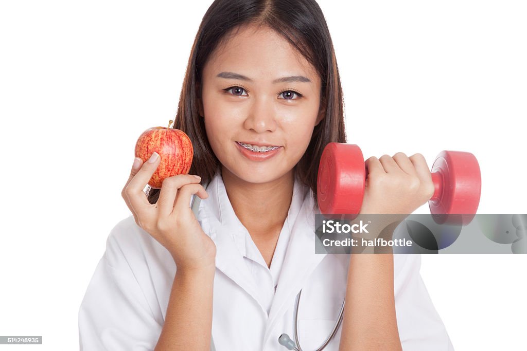 Young Asian female doctor  hold apple and dumbbell Young Asian female doctor  hold apple and dumbbell  isolated on white background Adult Stock Photo